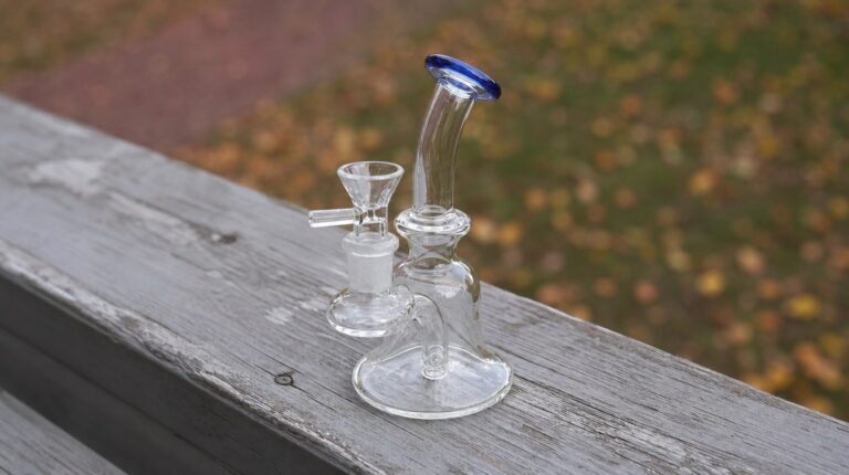 Roots Glass 6-inch Jammer mini dab rig with a blue lip resting on a weathered porch rail in soft autumn daylight.